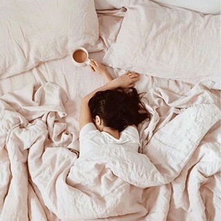 woman sleeping on bed, coffee cup in hand
